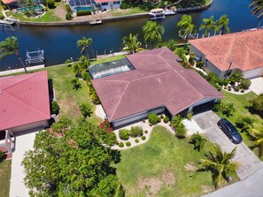 Un barrio residencial con una casa que tiene techo de tejas rojas, piscina y un muelle.