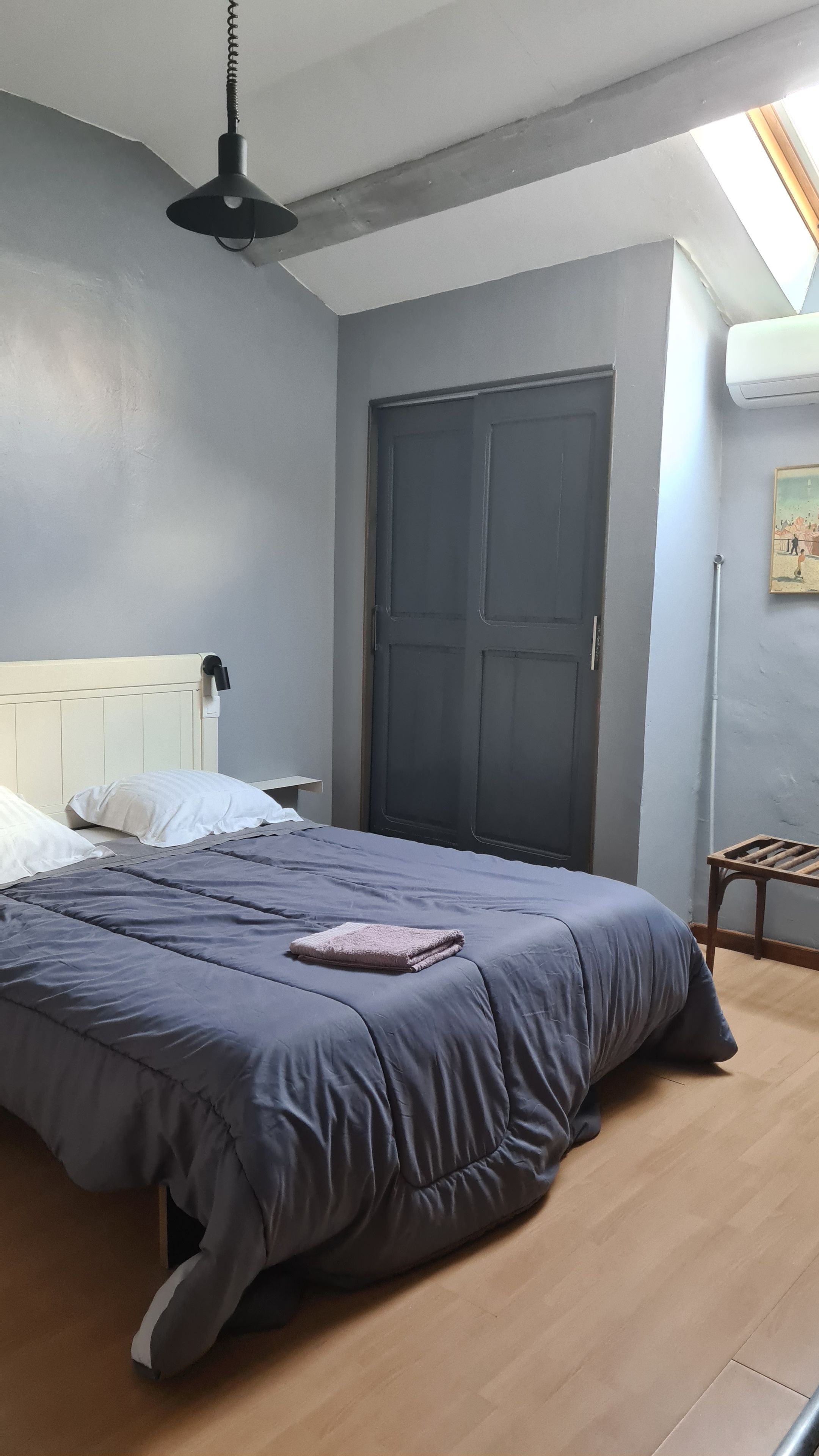A bedroom with a bed, a bedside lamp, a door, and a small table.