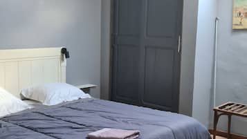 A bedroom with a bed, a bedside lamp, a door, and a small table.