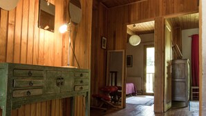 Un intérieur en bois avec une commode verte, un miroir et une porte donnant sur une autre pièce.