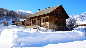 Un chalet en bois doté d’un balcon, entouré de montagnes enneigées.