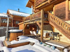 Une cabane en bois dotée d’un bain à remous, d’un espace extérieur aménagé et d’un mur en pierre.