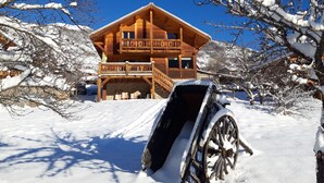 Een houten chalet met een balkon, omringd door met sneeuw bedekte bomen.