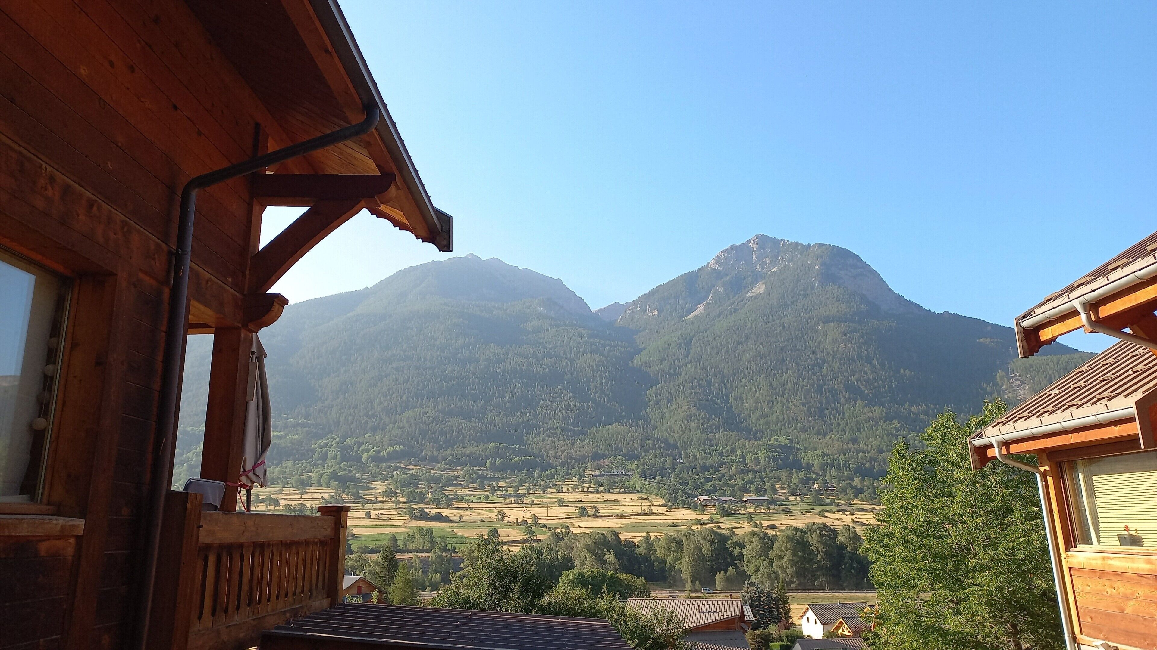 A wooden cabin with a balcony overlooking a valley and mountains.