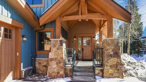 Un chalet en bois avec une entrée en pierre et un porche abrité.
