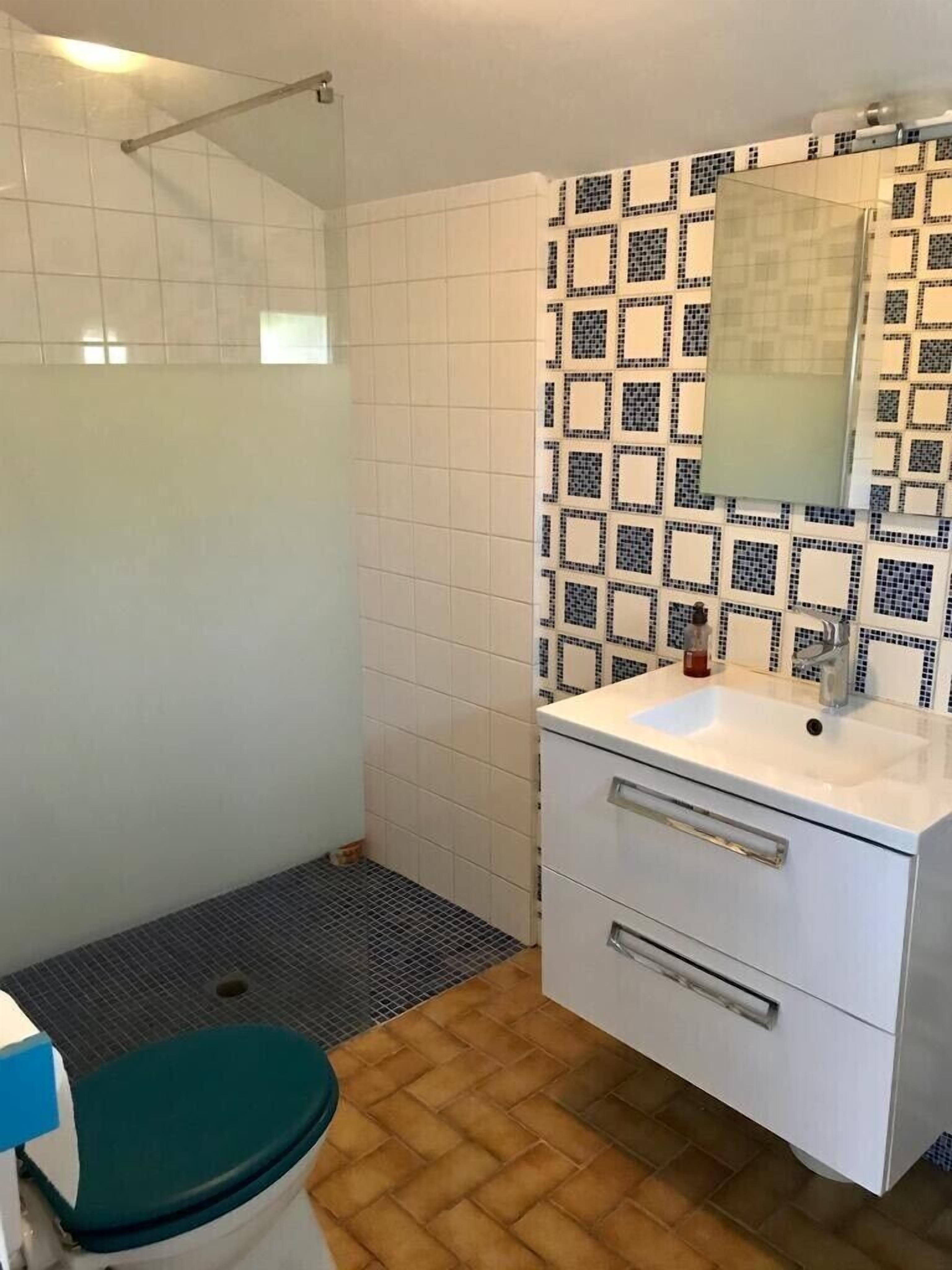 A bathroom with a shower, toilet, sink, and mirror.