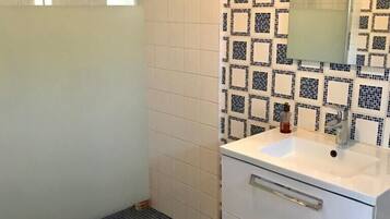 A bathroom with a shower, toilet, sink, and mirror.
