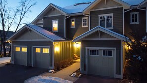 Ein zweistöckiges Haus mit Garage, überdachter Veranda und Schnee auf der Auffahrt.