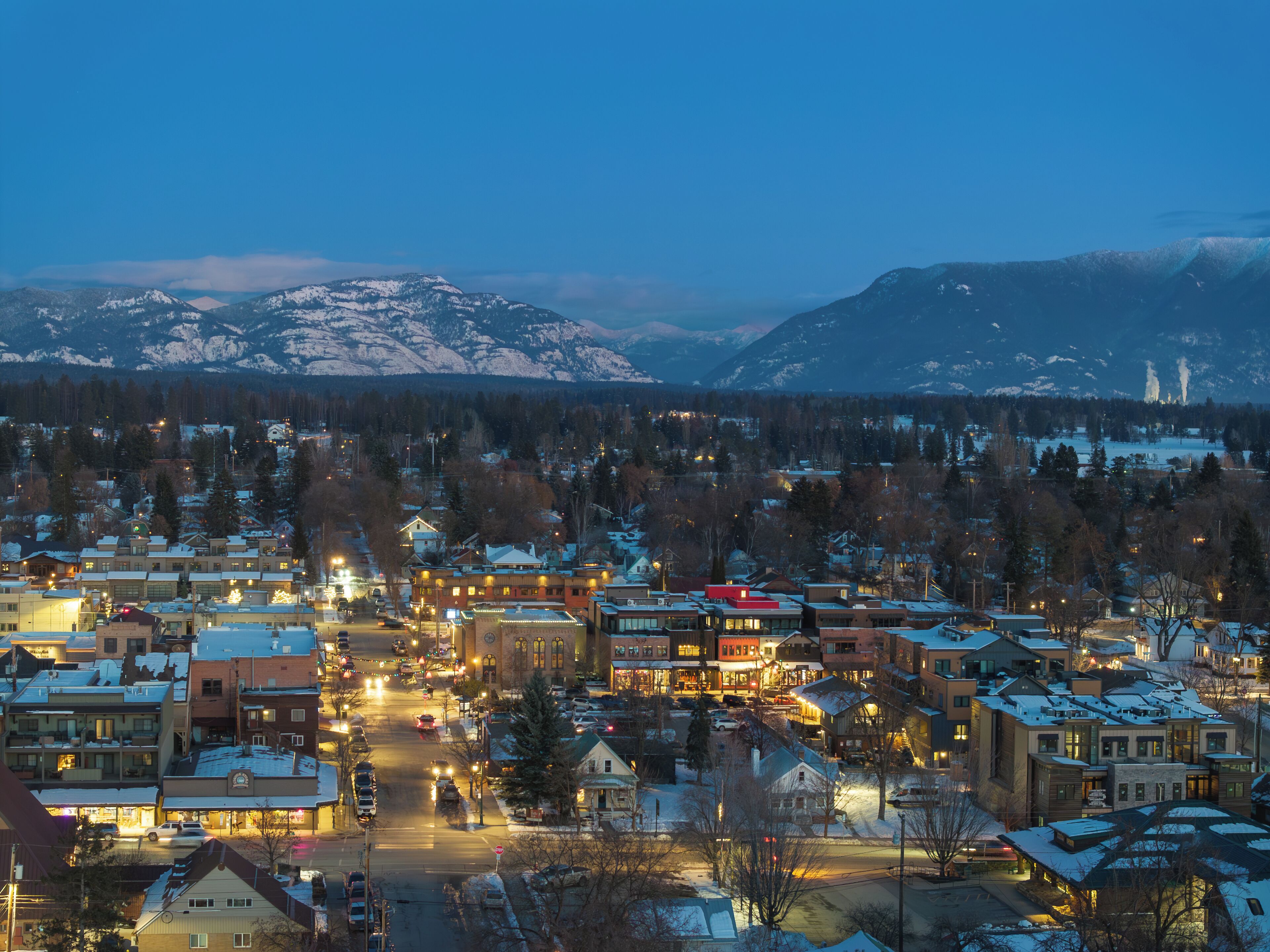 A town with buildings, roads, and snow-covered mountains in the background.