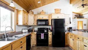 Une cuisine avec des meubles de rangement en bois, un réfrigérateur noir, une cuisinière et un four à micro-ondes.