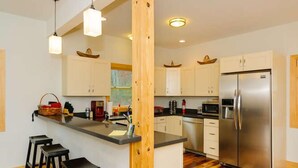 A modern kitchen with a central island, bar stools, stainless steel appliances, and wooden accents. - Epic Views! Immaculate Modern Cabin Just 10 Min. From Downtown! (Asheville)