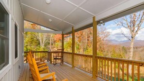 A covered porch with wooden railings and benches, overlooking a scenic landscape with trees and mountains. - Epic Views! Immaculate Modern Cabin Just 10 Min. From Downtown! (Asheville)