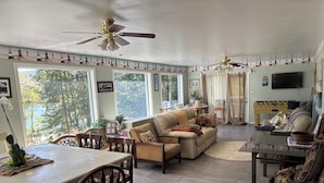 A spacious living area with a sofa, chairs, a dining table, and a TV.