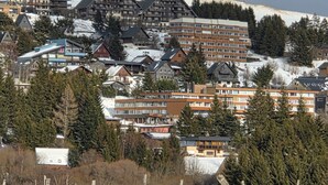 Un pueblo cubierto de nieve en la montaña con edificios modernos, incluyendo un hotel de varios pisos y balcones.