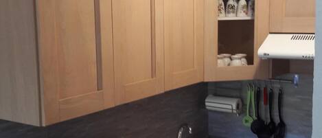 Una cocina moderna con armarios de madera, un lavamanos blanco, un tostador y una estufa.
