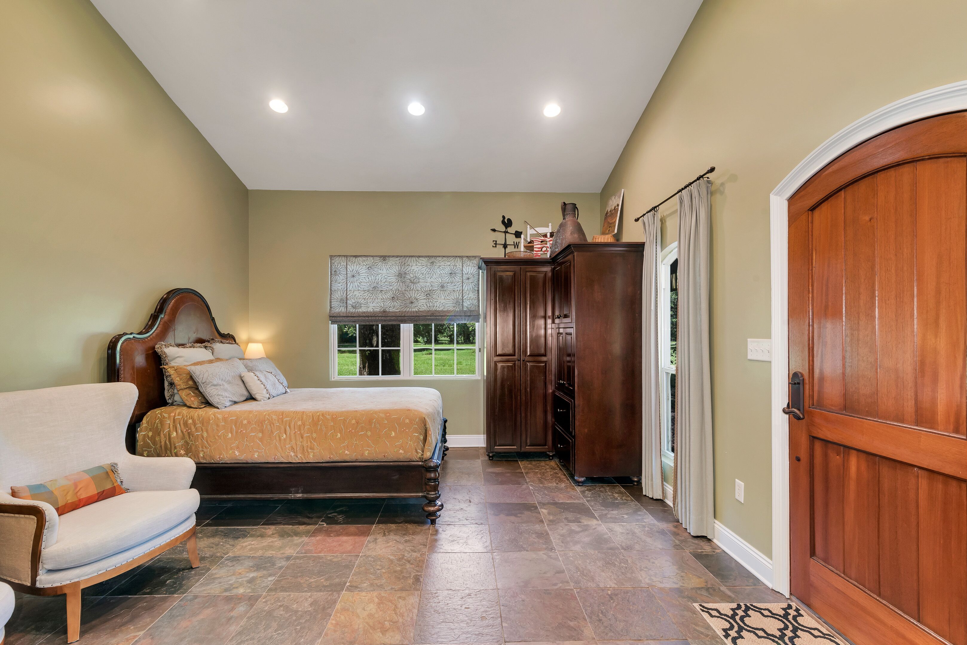 A bedroom with a bed, a chair, a wardrobe, and a door.