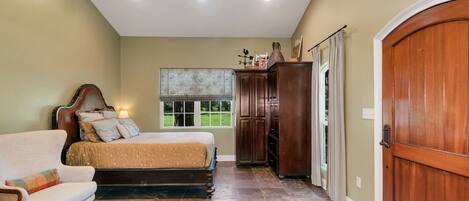 A bedroom with a bed, a chair, a wardrobe, and a door.