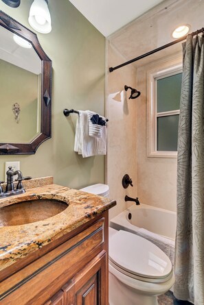 A bathroom with a granite sink, a white toilet, a bathtub, and a shower curtain. - Farm Stay: Come Stay With Us (Fairhope)
