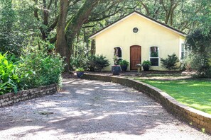 A yellow building with a brick pathway leading to it, surrounded by greenery. - Farm Stay: Come Stay With Us (Fairhope)
