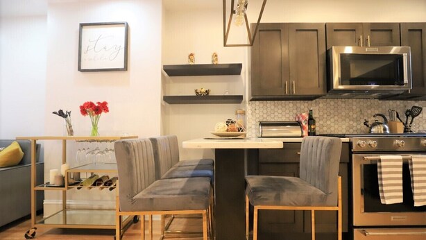 Een moderne keuken met een ingebouwde magnetron, oven en een eethoek met een glazen tafel en comfortabele stoelen.