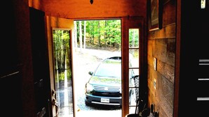 A wooden door leading to a stone-paved entrance with a hanging light fixture. - Luxurious, rustic, private vacation home with great view. (Davis)