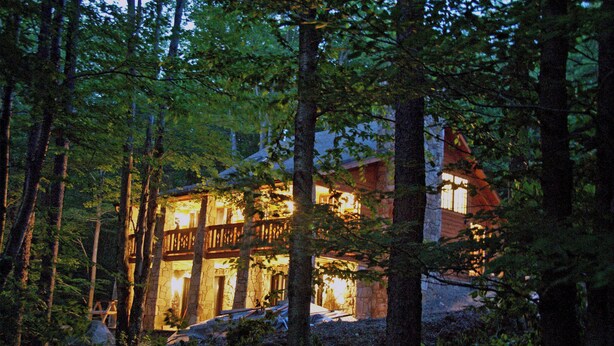 A cabin with a stone exterior, surrounded by dense forest. - Luxurious, rustic, private vacation home with great view. (Davis)