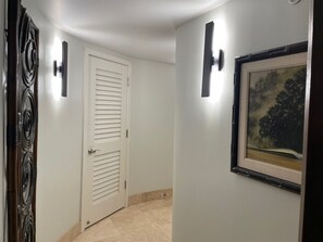 Ein Flur mit einer weißen Tür, einem Bild an der Wand und einer Lampe.