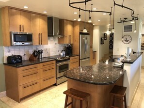 Enjoy cooking in this well-equipped kitchen with a central island, bar stools, and stainless steel appliances.