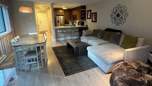 A modern living room with a dining area, a kitchen, and a cozy seating area with a dog bed. - Negotiable! Hot tub, new kitchen and master bath.  (Frisco)