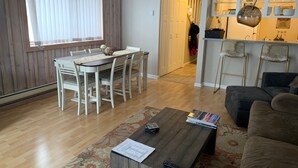 A dining area with a wooden table and chairs, a coffee table with a remote control, and a sofa in a living room. - Negotiable! Hot tub, new kitchen and master bath.  (Frisco)