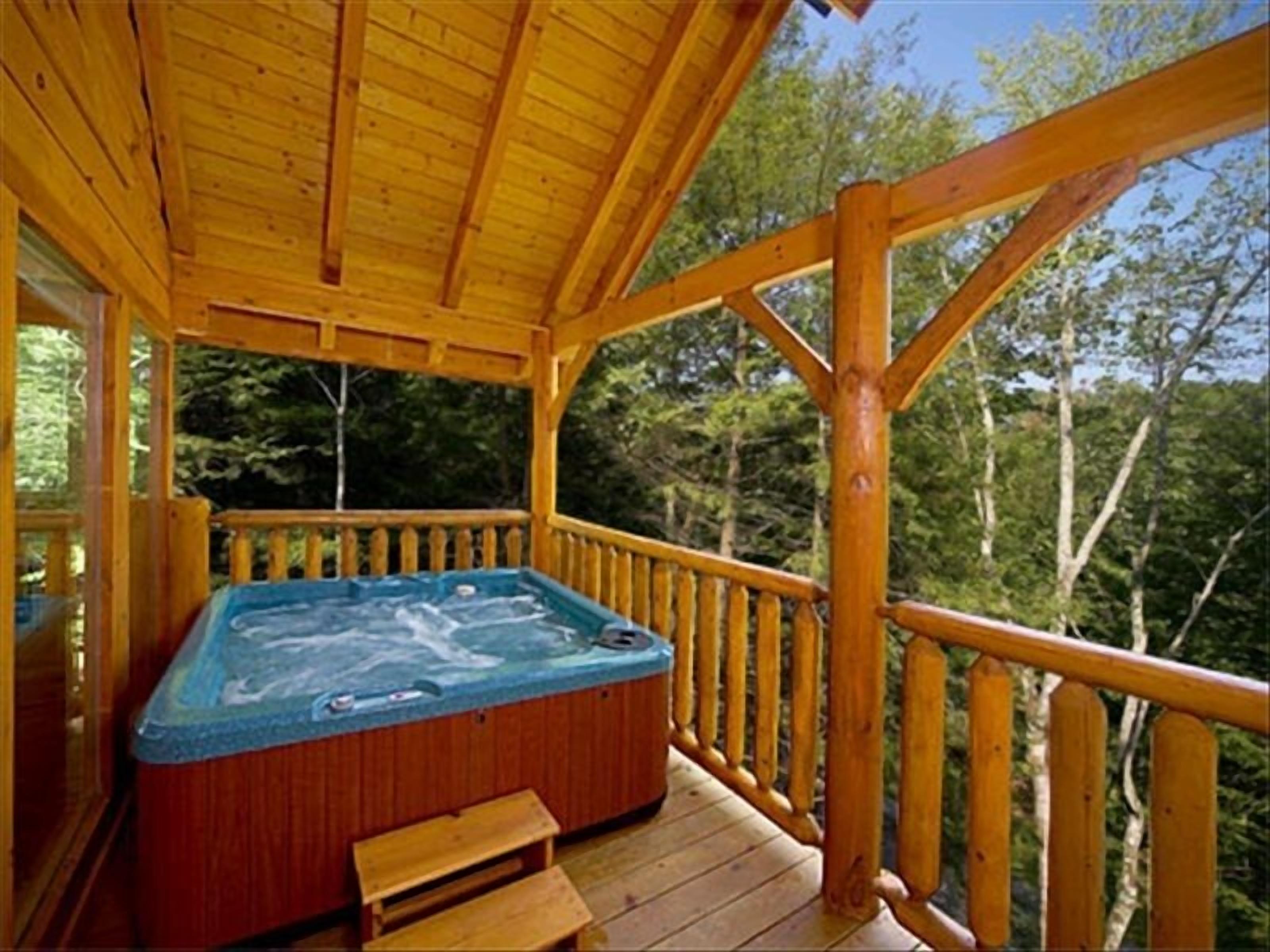 A wooden deck with a hot tub, wooden railings, and a bench.