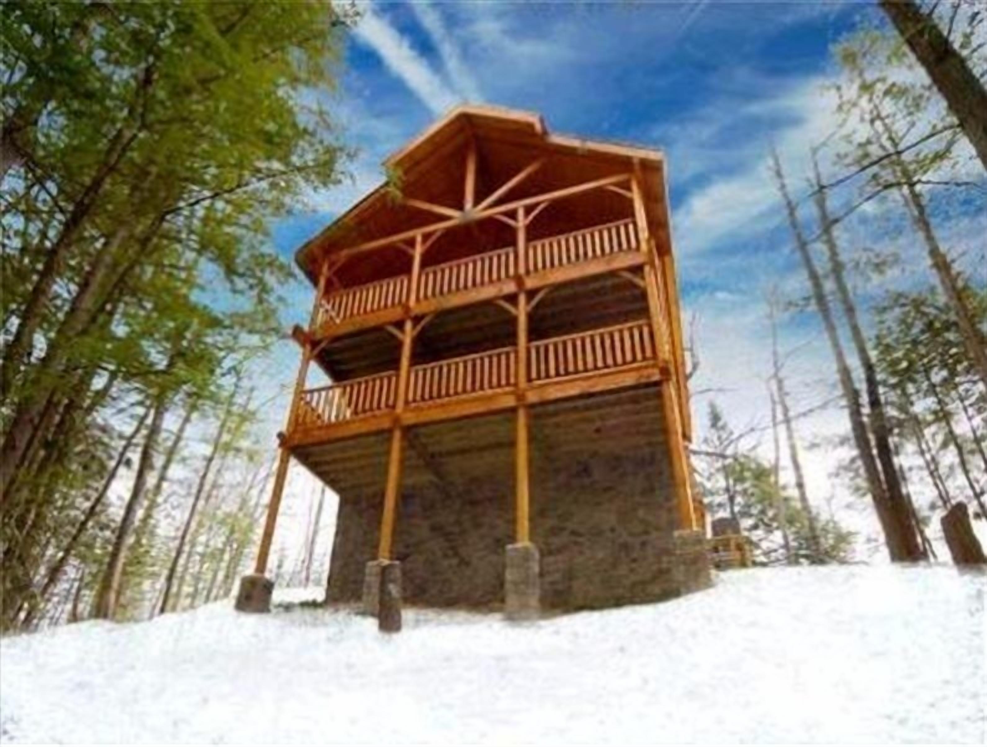 A wooden cabin with a balcony, surrounded by trees and snow.