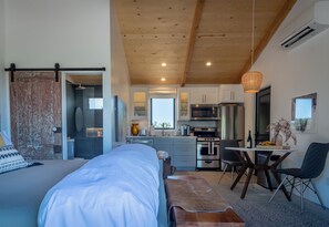 A modern bedroom with a large bed, a wooden ceiling, and a sliding door leading to a bathroom. - Gated Vineyard Ranch + Fire Pit | Paso Robles | Cocavin Carriage House (Paso Robles)