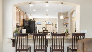 Una cocina con una isla central, sillas de madera e iluminación colgante.