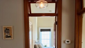 A hallway with a wooden floor leading to a bedroom with a bed and a window. - Decorah House- Airy, modern, full of natural light, 5 blocks to downtown (Decorah)