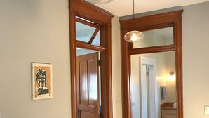 A hallway with wooden doors, a red patterned rug, and a ceiling fan. - Decorah House- Airy, modern, full of natural light, 5 blocks to downtown (Decorah)