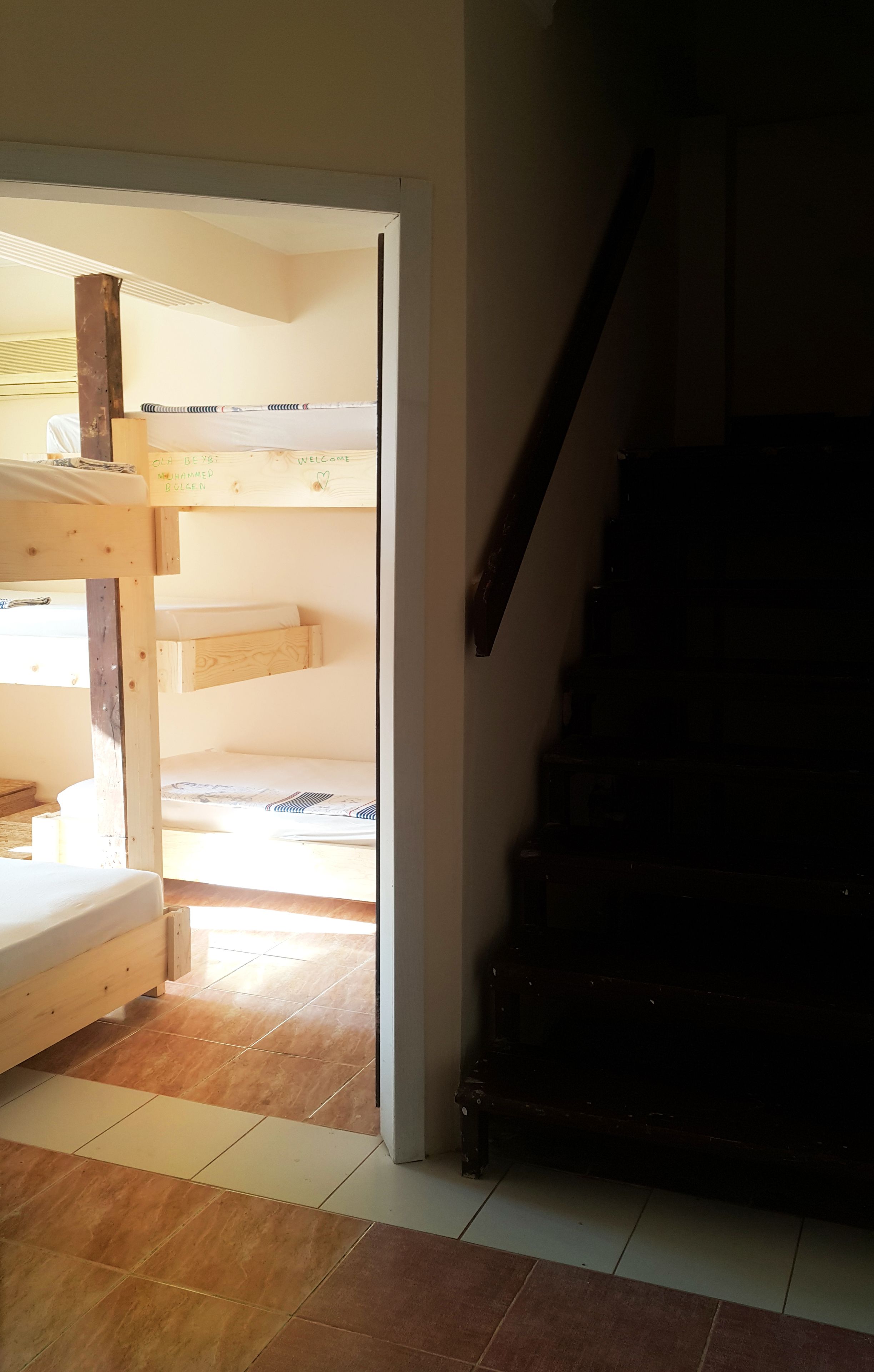 Ein Zimmer mit einem Etagenbett, einer Holztreppe und einem Fliesenboden.