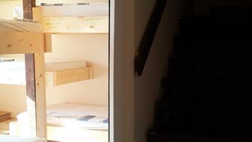 A room with a bunk bed, a wooden staircase, and a tiled floor.
