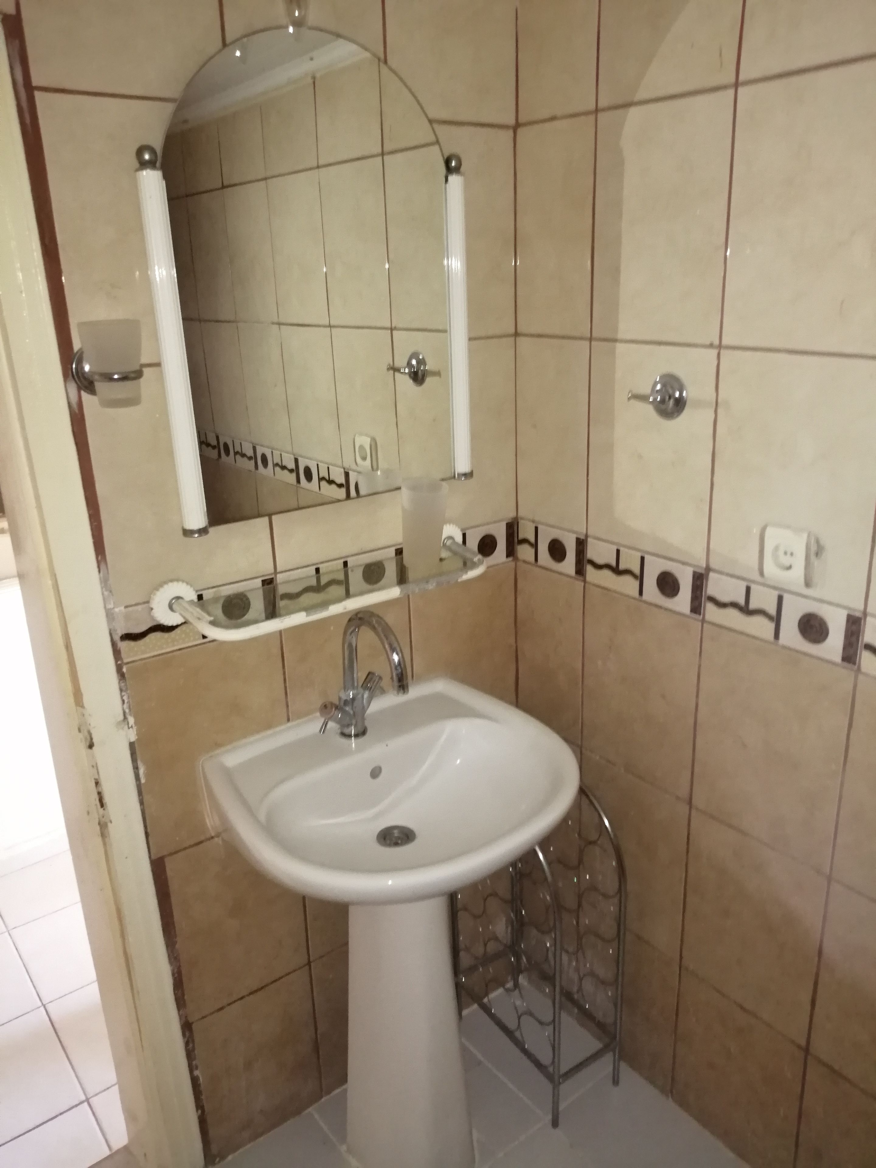 A bathroom with a white sink, a mirror, and a towel rack.