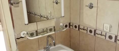 A bathroom with a white sink, a mirror, and a towel rack.