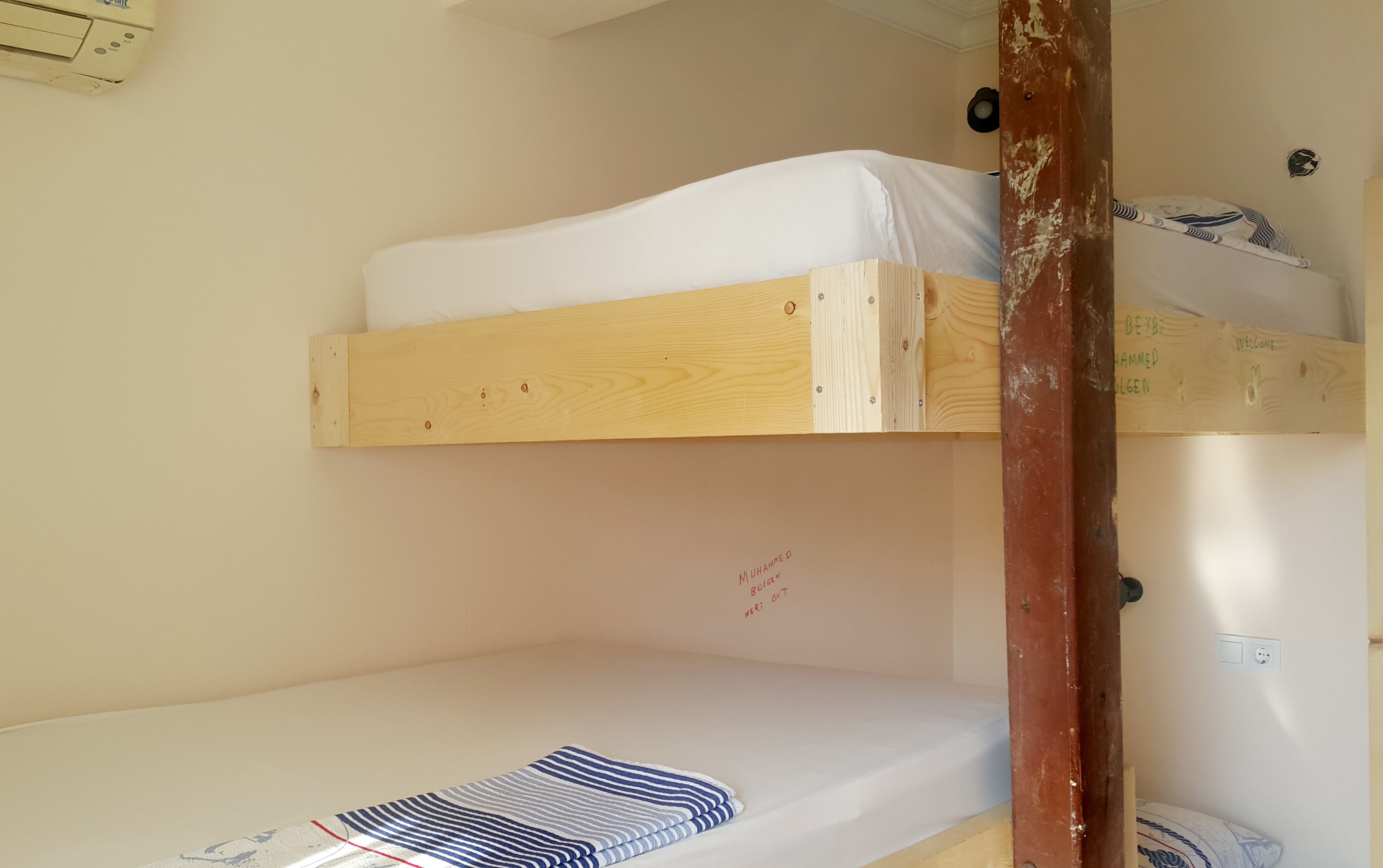 A bunk bed with a white mattress and a striped blanket.
