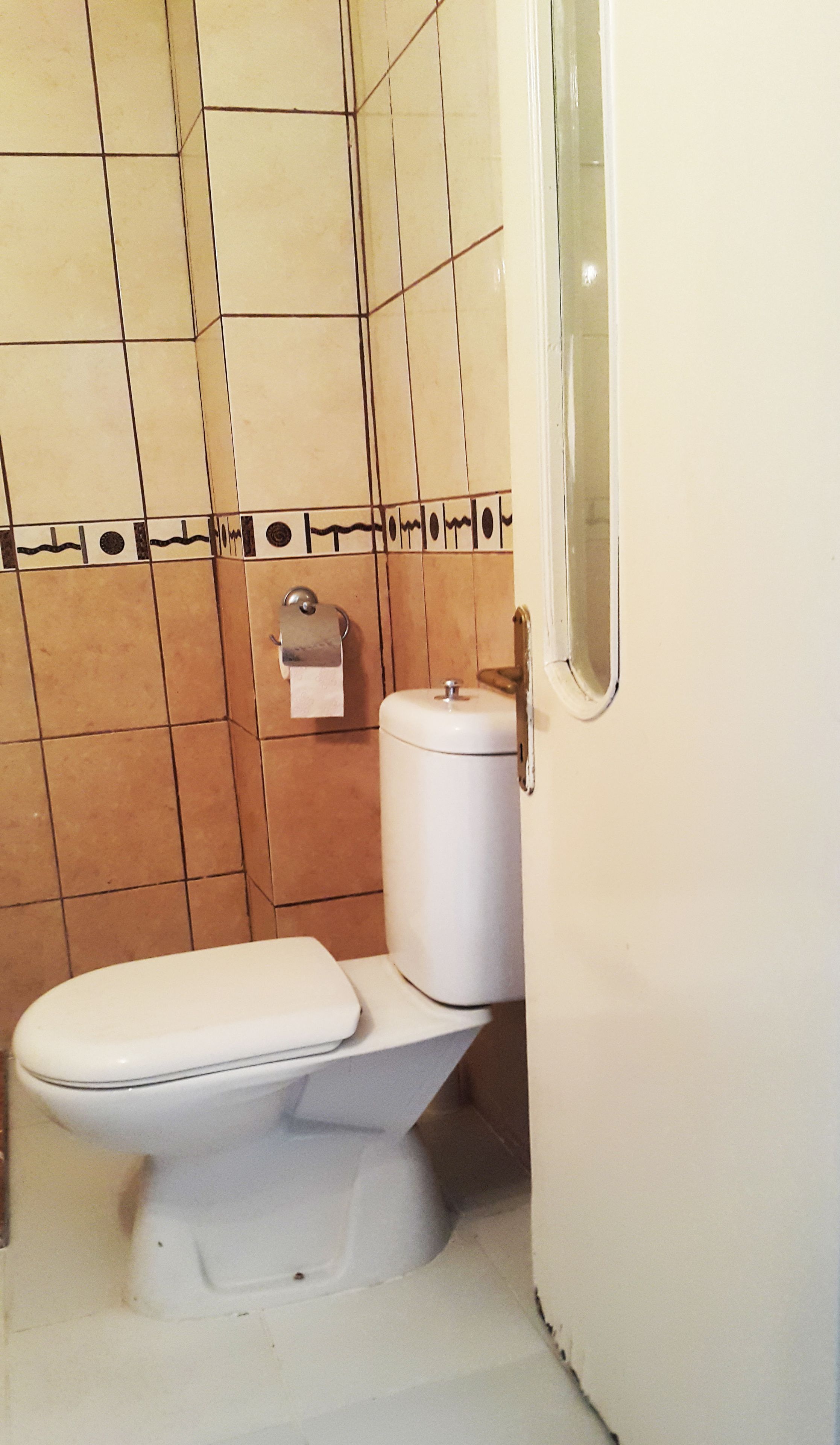 A small bathroom with a toilet, a paper towel dispenser, and a white door.