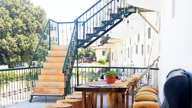 A terrace with a staircase, wooden stools, lounge chairs, and a table with a potted plant. - Oludeniz Hostel (Fethiye)