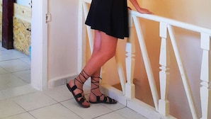 A woman in a black dress standing by a white railing in a room with tiled flooring. - Oludeniz Hostel (Fethiye)