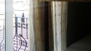 A room with a bunk bed, a window with curtains, and a view of a street and mountains outside. - Oludeniz Hostel (Fethiye)