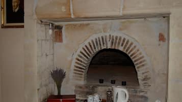 A brick fireplace with a tray holding a teapot, cups, and a glass carafe.