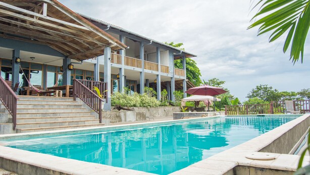 Una piscina con un muelle de madera y escaleras que conducen a un área cubierta con barandilla.