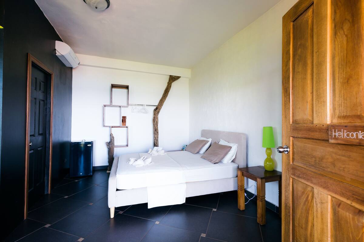 A bedroom with a bed, bedside table, lamp, and a wooden door with a sign.