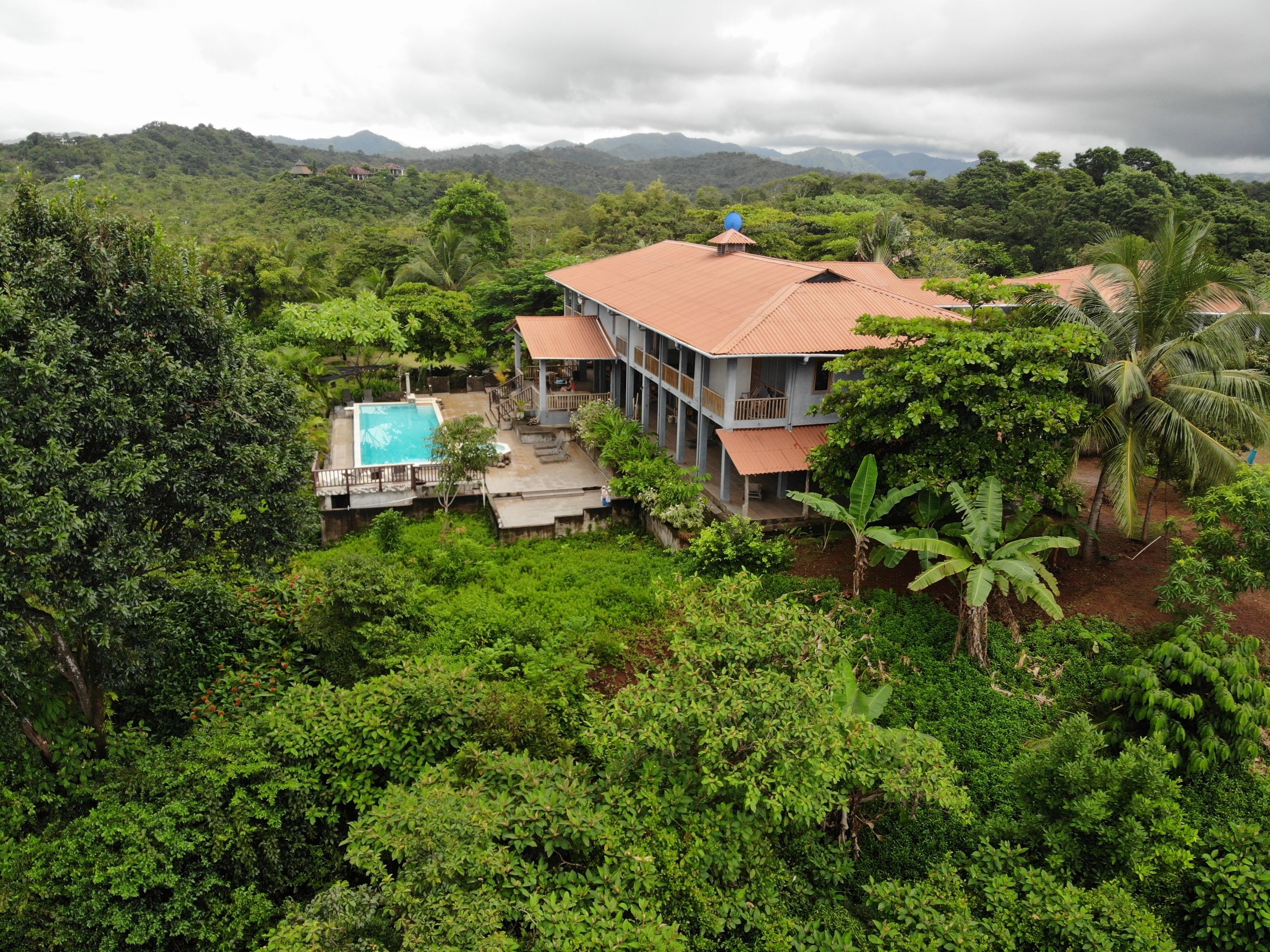 Una casa de dos pisos con piscina y vistas al bosque y las montañas circundantes.