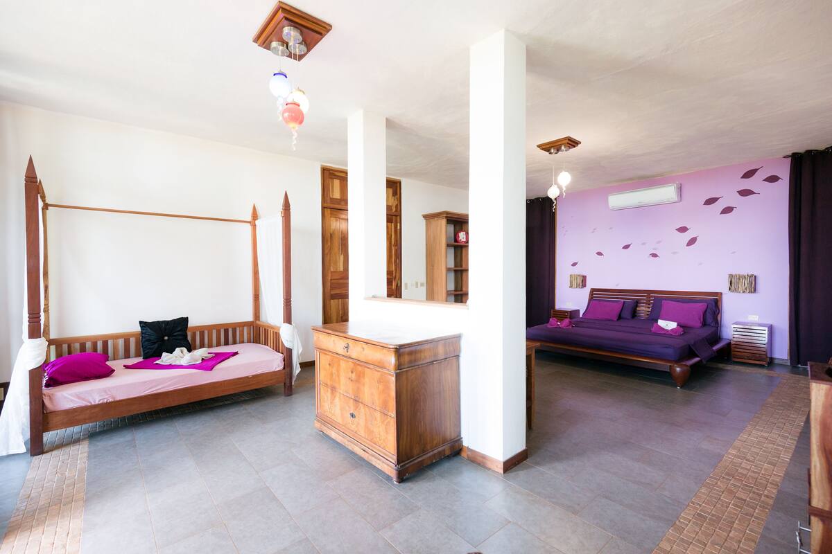 A bedroom with a four-poster bed, a wooden dresser, and a two-poster bed.